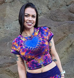 Woman wearing tie-dye outfit standing against a stone wall